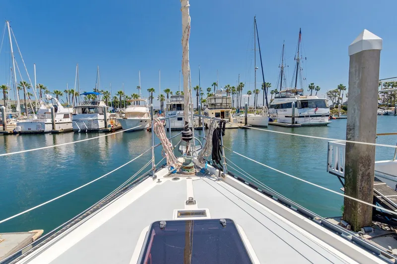 Slide: The Image of 1987 Macintosh Center Cockpit sailboat docked in a sunny marina with palm trees. - 42