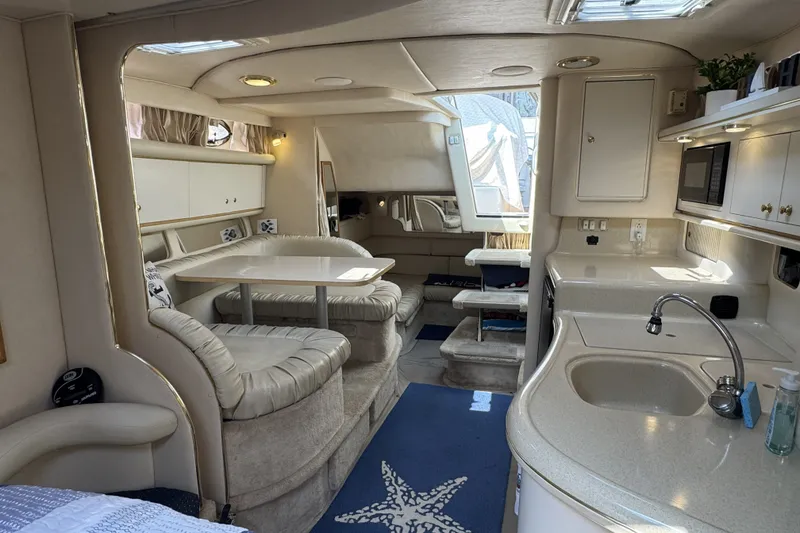 Slide: The Image of Interior of a 2000 Sea Ray 340 Sundancer yacht, featuring a cozy dining area and kitchenette. - 15