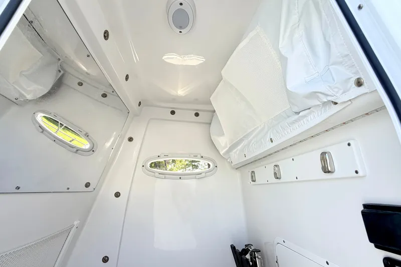 Slide: The Image of Interior cabin of 2027 Sea Hunt Ultra 285SL boat, featuring sleek white design and porthole windows. - 31