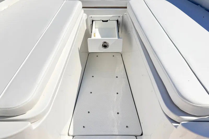 Slide: The Image of 2027 Sea Hunt Ultra 285SL boat interior with white cushioned seating and storage compartment. - 27