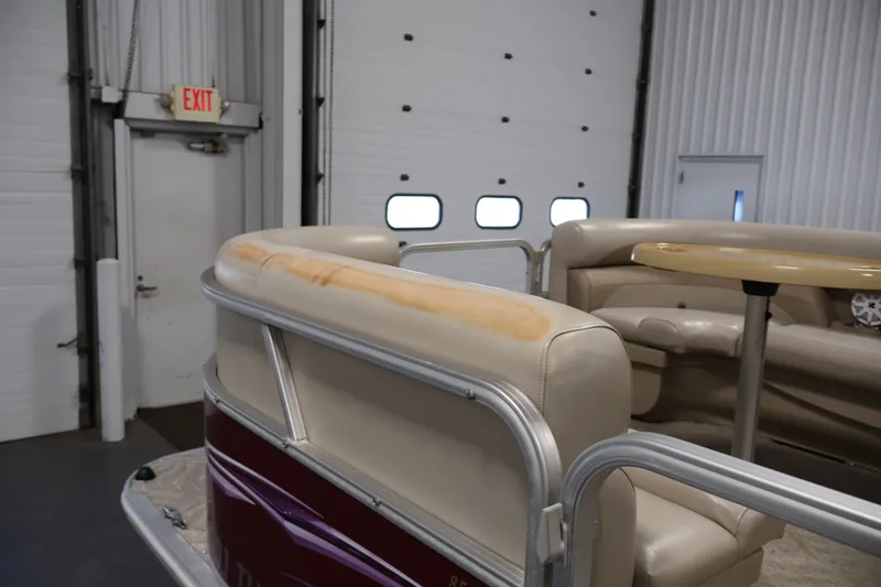 Slide: The Image of 2011 Sylvan Mirage 8520 pontoon boat interior with beige seating and table in a garage. - 44