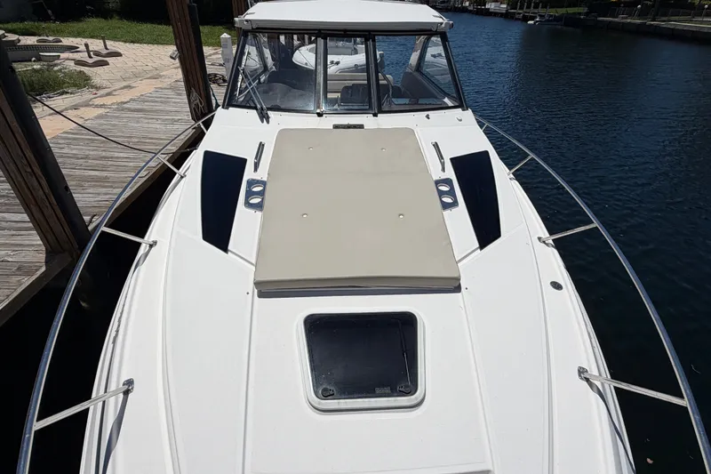 Slide: The Image of 2015 Regal 35 Sport Coupe boat docked by the water, featuring a spacious deck. - 4