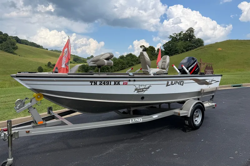The Image of 2001 Lund 1775 Pro-V boat on trailer, parked outdoors with scenic background. - 0