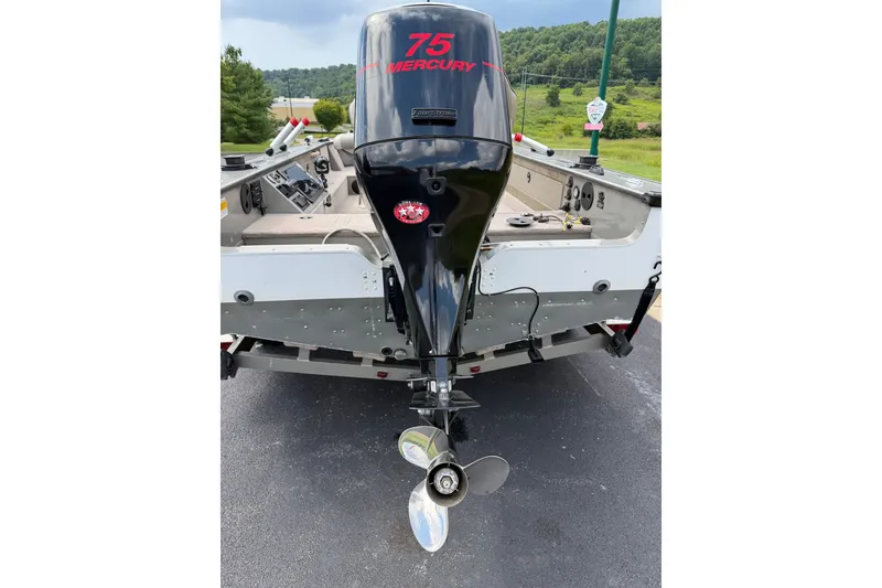 Slide: The Image of 2001 Lund 1775 Pro-V boat with Mercury 75 outboard motor, parked on pavement. - 2