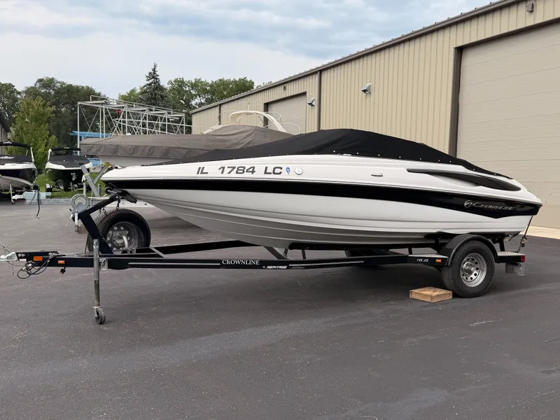 The Image of 2009 Crownline 185 SS on a trailer, covered, parked in front of a warehouse. - 0