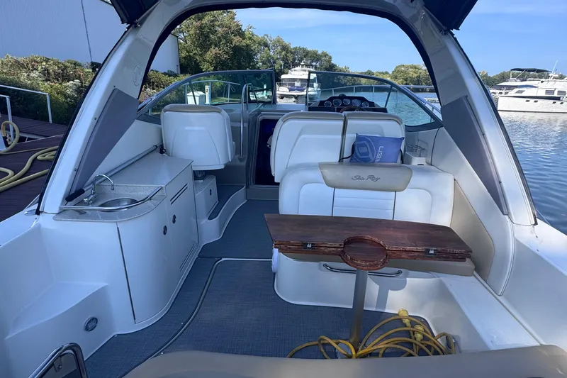 Slide: The Image of 2008 Sea Ray 350 Sundancer interior with seating, table, and kitchenette by the water. - 6
