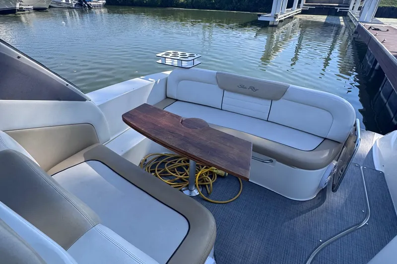 Slide: The Image of 2008 Sea Ray 350 Sundancer boat interior with seating and wooden table, docked by the water. - 25