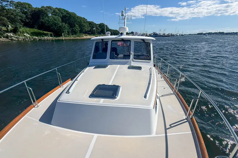 Slide: The Image of 2003 Grand Banks 38 Eastbay HX yacht cruising on a sunny day, near a lush shoreline. - 42