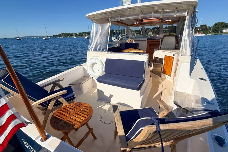 Slide: The Image of 2008 True North 34 boat with blue seating, wooden table, and scenic harbor view. - 6