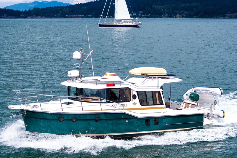 The Image of 2016 Ranger Tug 29 cruising on a scenic lake with sailboat in background. - 0