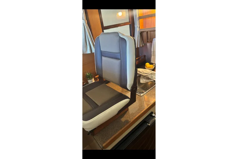 Slide: The Image of 2015 Ranger Tugs R-25 SC interior with a cushioned seat and kitchenette area. - 36