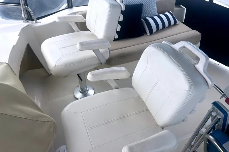 Slide: The Image of Interior of 2008 Mainship 34 Trawler with white captain chairs and striped cushions. - 31