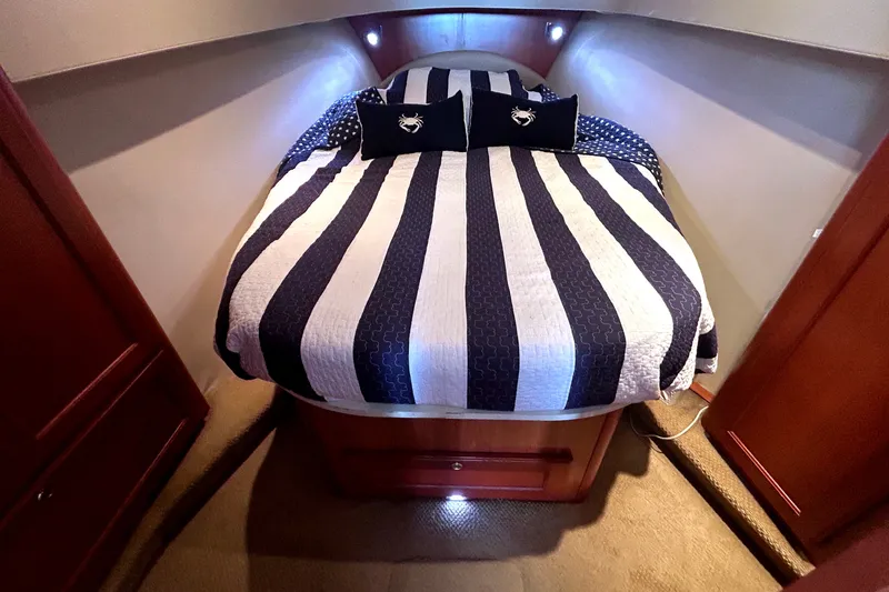 Slide: The Image of Cozy cabin interior of 2008 Mainship 34 Trawler with striped bedding and wooden accents. - 22