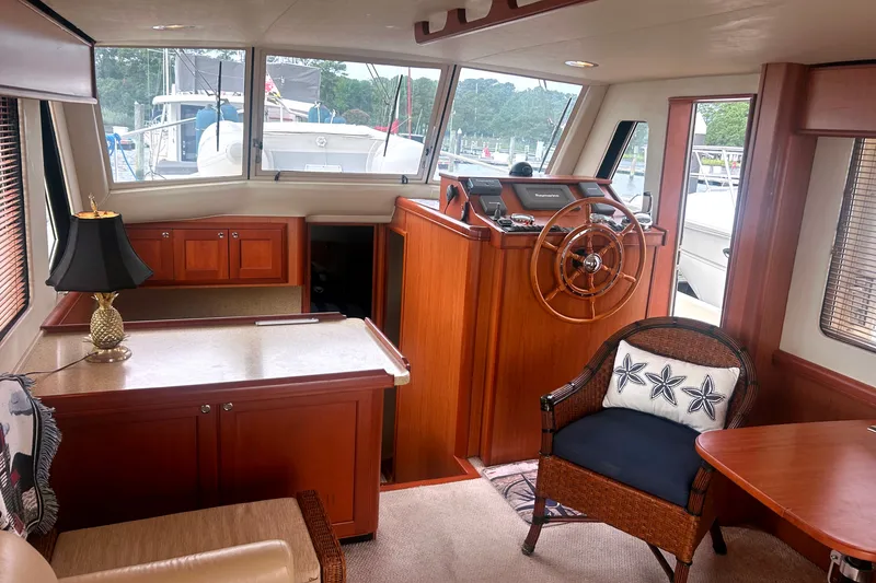 Slide: The Image of Interior of 2008 Mainship 34 Trawler with wooden helm, seating, and nautical decor. - 9
