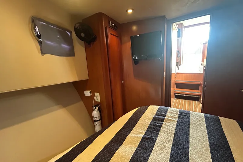 Slide: The Image of Cozy cabin interior of 2008 Mainship 34 Trawler with striped bedding and wall-mounted TV. - 23