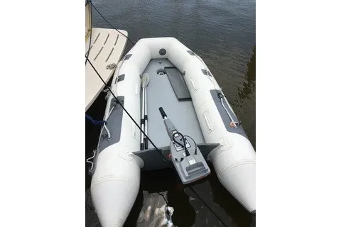 Slide: The Image of Inflatable dinghy docked beside a 2008 Mainship 34 Trawler on calm water. - 47