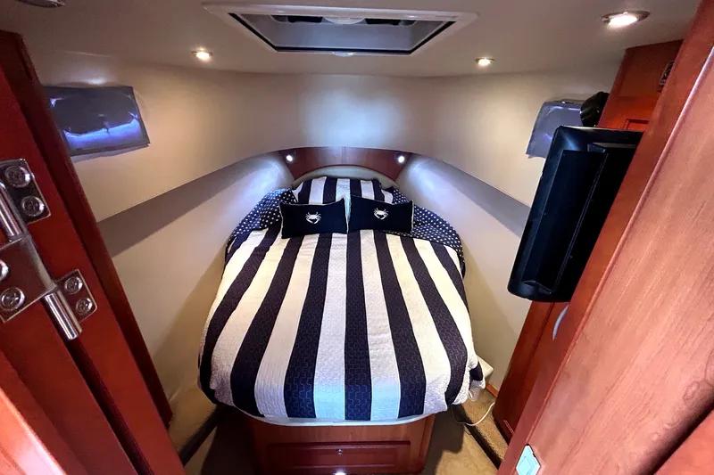 Slide: The Image of Cozy cabin interior of 2008 Mainship 34 Trawler with striped bedding and ambient lighting. - 21