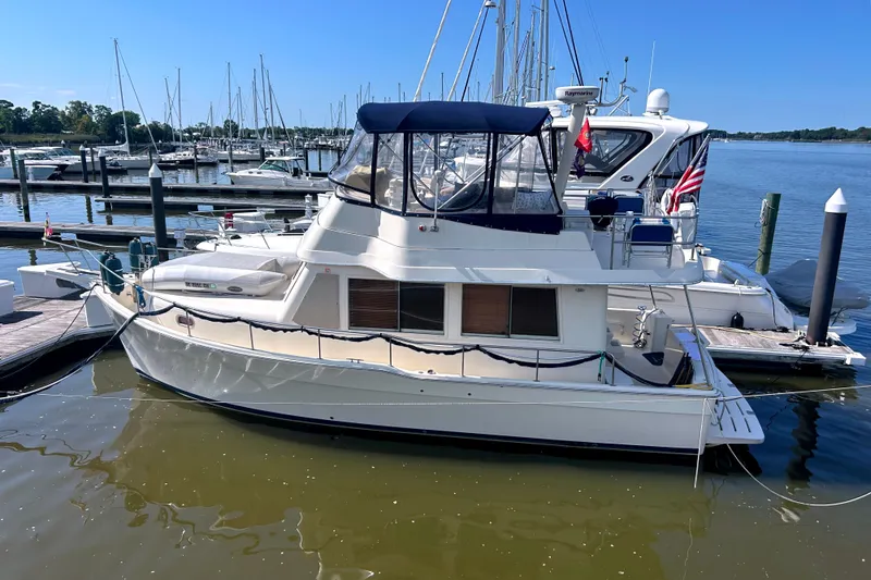 Slide: The Image of 2008 Mainship 34 Trawler docked at marina, surrounded by sailboats under clear blue sky. - 1