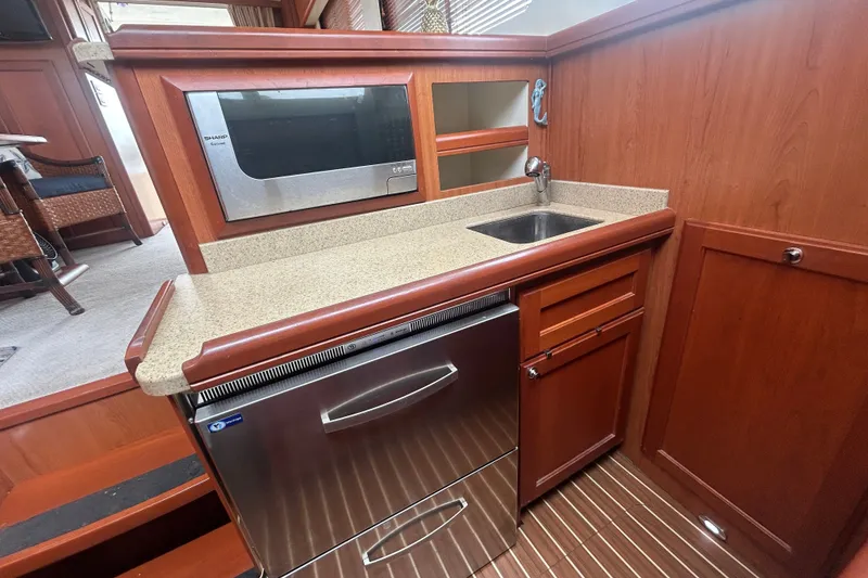 Slide: The Image of 2008 Mainship 34 Trawler kitchen with microwave, sink, and wooden cabinetry. - 16