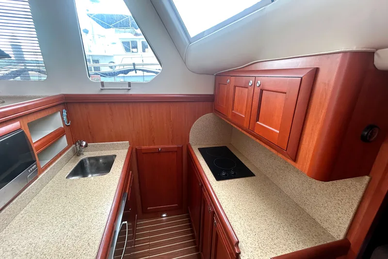 Slide: The Image of 2008 Mainship 34 Trawler kitchen with wood cabinets, sink, and stovetop. - 18