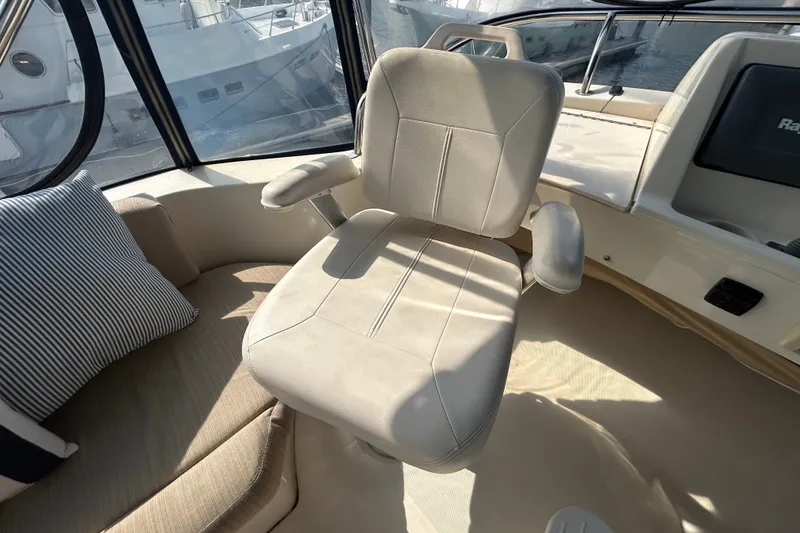 Slide: The Image of Captain's chair in 2008 Mainship 34 Trawler cockpit, with striped cushion and window view. - 32