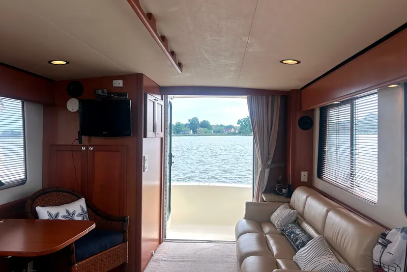 Slide: The Image of Interior of 2008 Mainship 34 Trawler with lake view, featuring cozy seating and a TV. - 8
