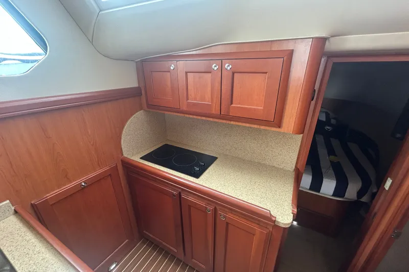 Slide: The Image of 2008 Mainship 34 Trawler interior kitchen with wooden cabinets and electric stove. - 17