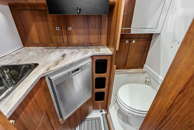 Slide: The Image of 2018 Invincible 42 Center Cabin interior with wood cabinetry, compact kitchen, and marine toilet. - 38