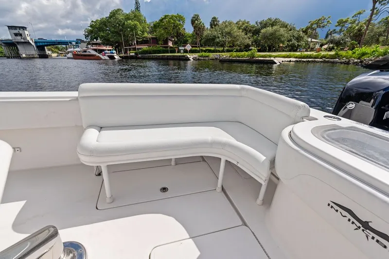 Slide: The Image of 2018 Invincible 42 Center Cabin boat with white seating, docked by a scenic waterfront. - 16