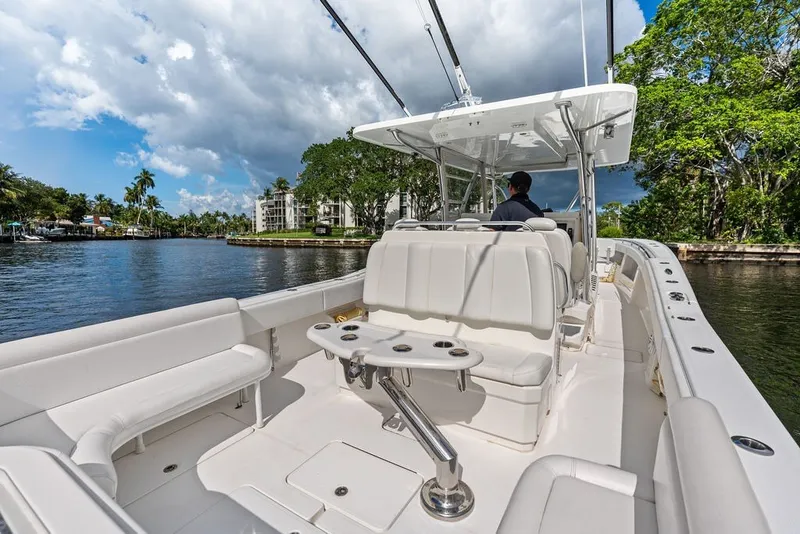 Slide: The Image of 2018 Invincible 42 Center Cabin boat cruising on a scenic waterway under a partly cloudy sky. - 19