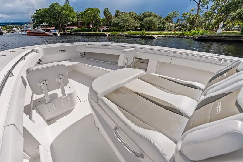 Slide: The Image of 2018 Invincible 42 Center Cabin boat interior with seating, docked by a scenic waterway. - 29