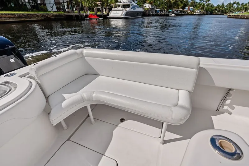 Slide: The Image of Invincible 42 Center Cabin 2018 boat with white seating, docked by a scenic waterfront. - 15