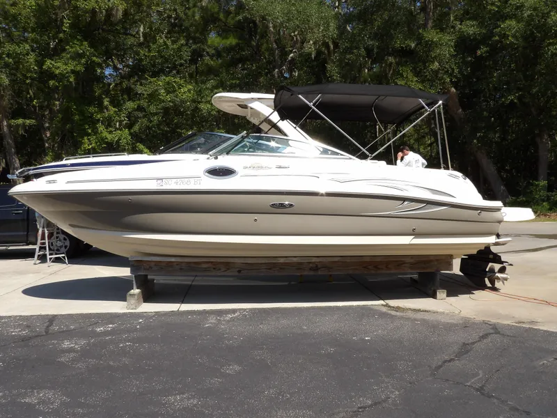 The Image of 2005 Sea Ray 240 Sundeck boat on a trailer, parked outdoors. - 0