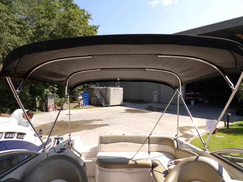 Slide: The Image of 2005 Sea Ray 240 Sundeck with bimini top in a sunny outdoor setting. - 27
