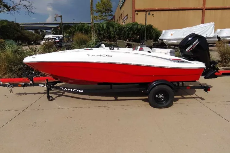The Image of Red and white 2027 Tahoe T16 boat on trailer, parked outdoors. - 0