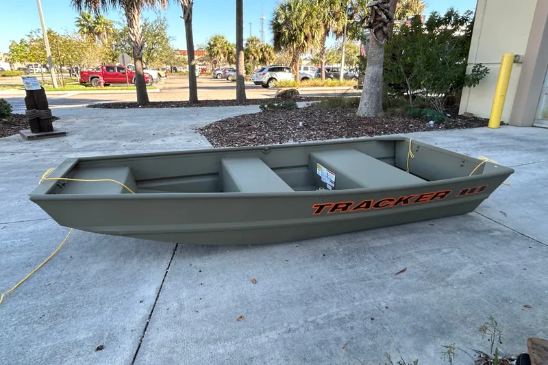 The Image of 2026 Tracker Grizzly 10 Jon boat on concrete, surrounded by trees and parked cars. - 0