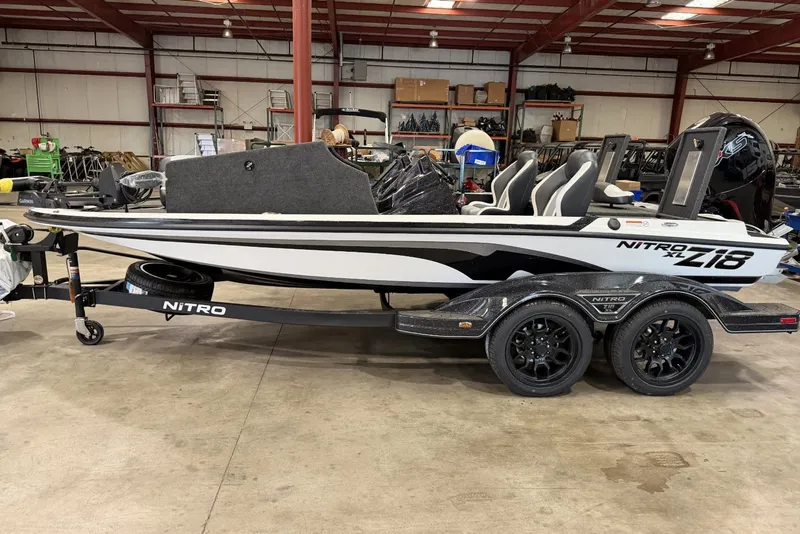The Image of 2027 Nitro Z18 XL Pro boat in a warehouse, featuring sleek design and dual-axle trailer. - 0