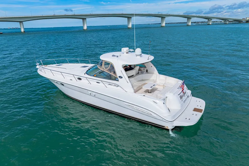 Slide: The Image of 2002 Sea Ray Sundancer 460 yacht cruising under a bridge on clear blue waters. - 24
