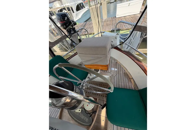 Slide: The Image of 1983 Tayana Aft Cockpit sailboat interior with green seating and wooden flooring at a marina. - 24