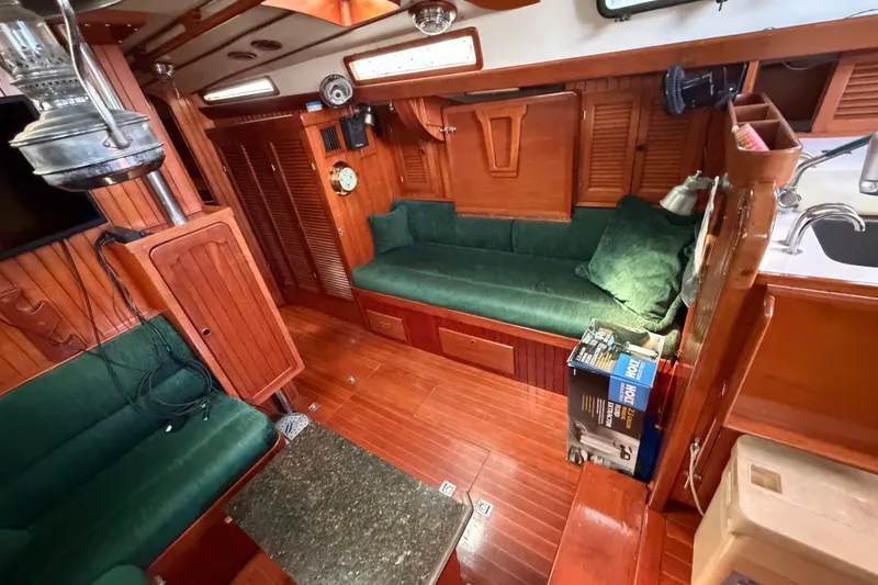 Slide: The Image of Interior of 1984 Tayana Aft Cockpit yacht with wooden finish and green upholstery. - 9