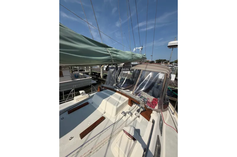 Slide: The Image of 1984 Tayana Aft Cockpit sailboat with green sail cover, docked under clear blue sky. - 18