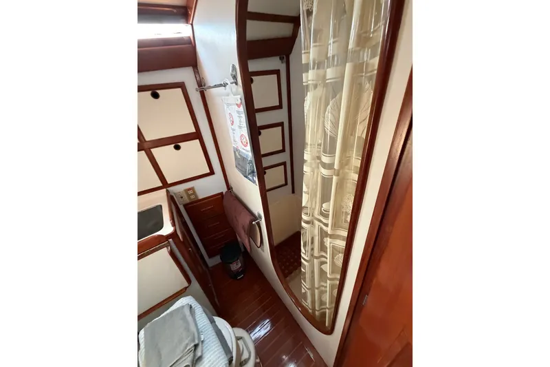 Slide: The Image of 1984 Tayana Aft Cockpit interior with shower, wooden accents, and nautical decor. - 16