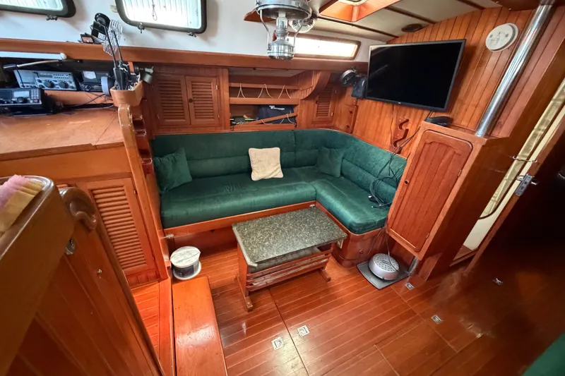Slide: The Image of Interior of 1984 Tayana Aft Cockpit yacht with green seating and wooden finishes. - 12