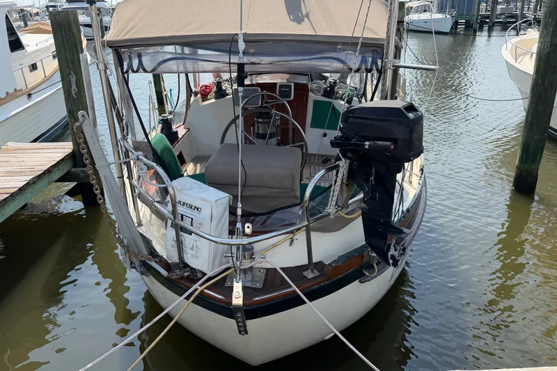 Slide: The Image of 1984 Tayana Aft Cockpit sailboat docked, featuring an outboard motor and covered cockpit. - 2