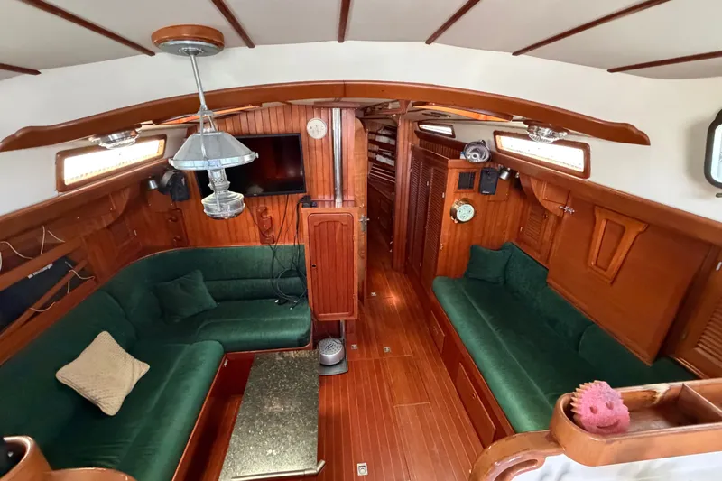 Slide: The Image of Interior of 1984 Tayana Aft Cockpit yacht with green seating and wooden finishes. - 14