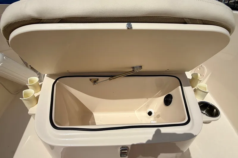 Slide: The Image of Open storage compartment on 2026 Grady-White Fisherman 180 boat, featuring cup holders and drain. - 7