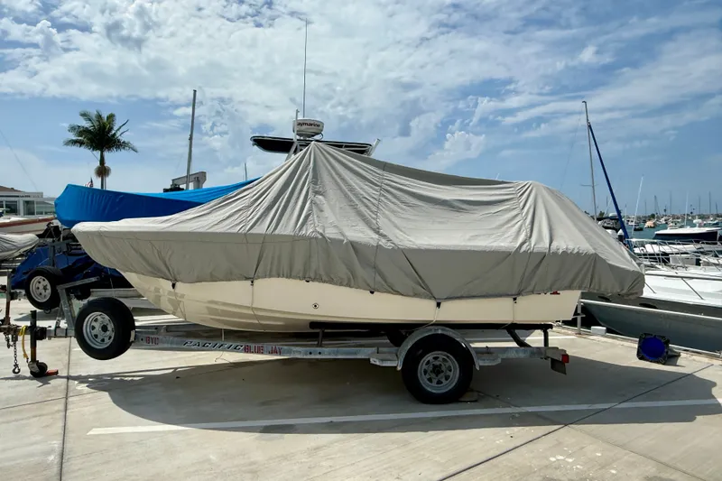 Slide: The Image of 2026 Grady-White Fisherman 180 boat covered on trailer at marina under cloudy sky. - 2