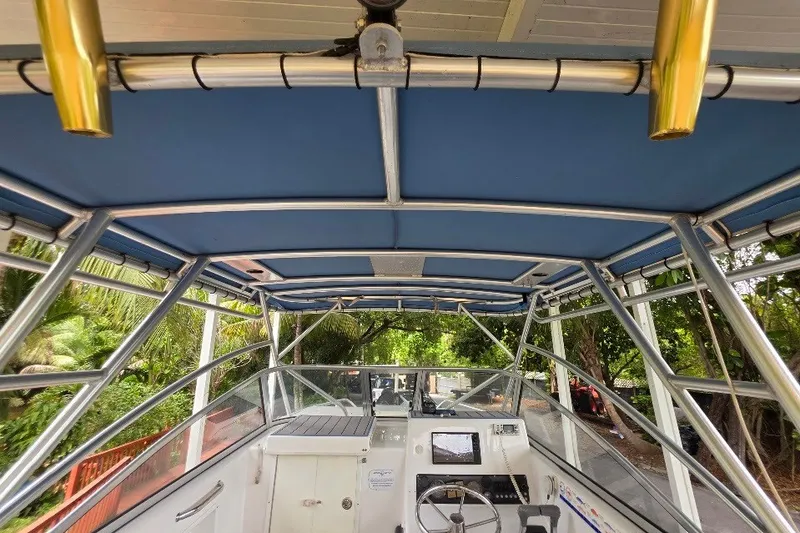Slide: The Image of 2006 Twin Vee 26 Express boat interior with blue canopy and steering console. - 26
