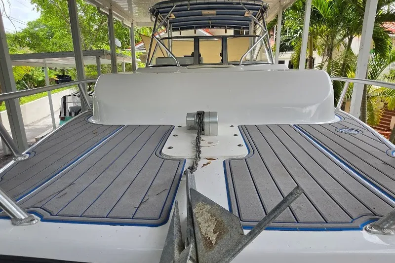 Slide: The Image of 2006 Twin Vee 26 Express boat deck with anchor and railing, surrounded by greenery. - 52
