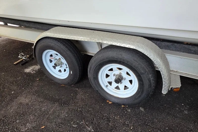 Slide: The Image of Trailer wheels of a 2006 Twin Vee 26 Express boat on asphalt surface. - 55